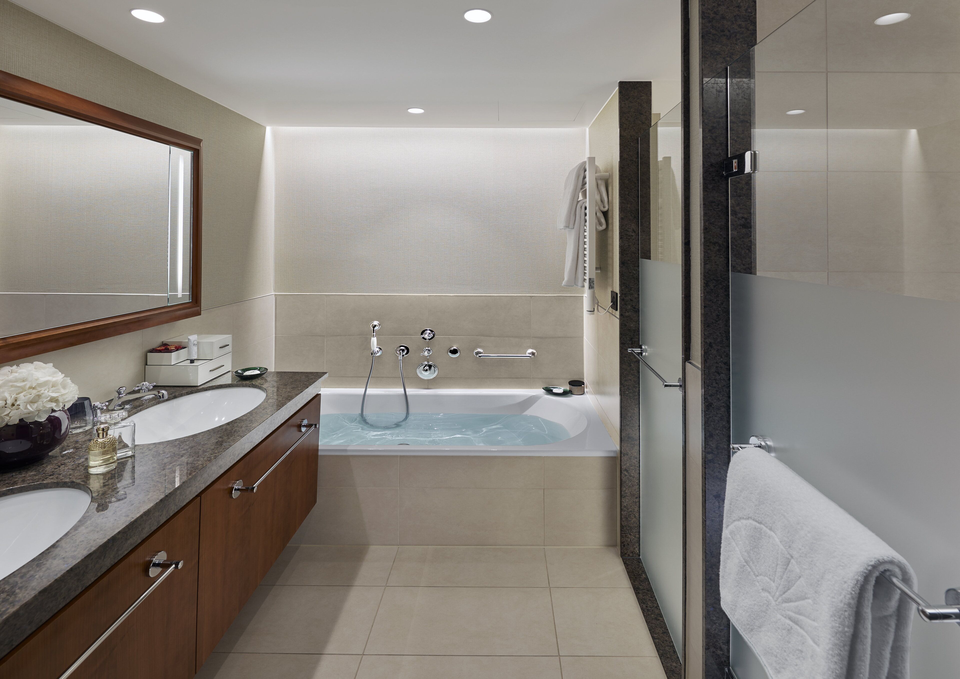 Un baño moderno con tocador doble, bañera independiente y zona de ducha con mampara de vidrio.