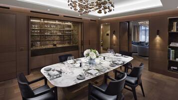 Un comedor moderno con una mesa de mármol, sillas negras y un aparador de vidrio.