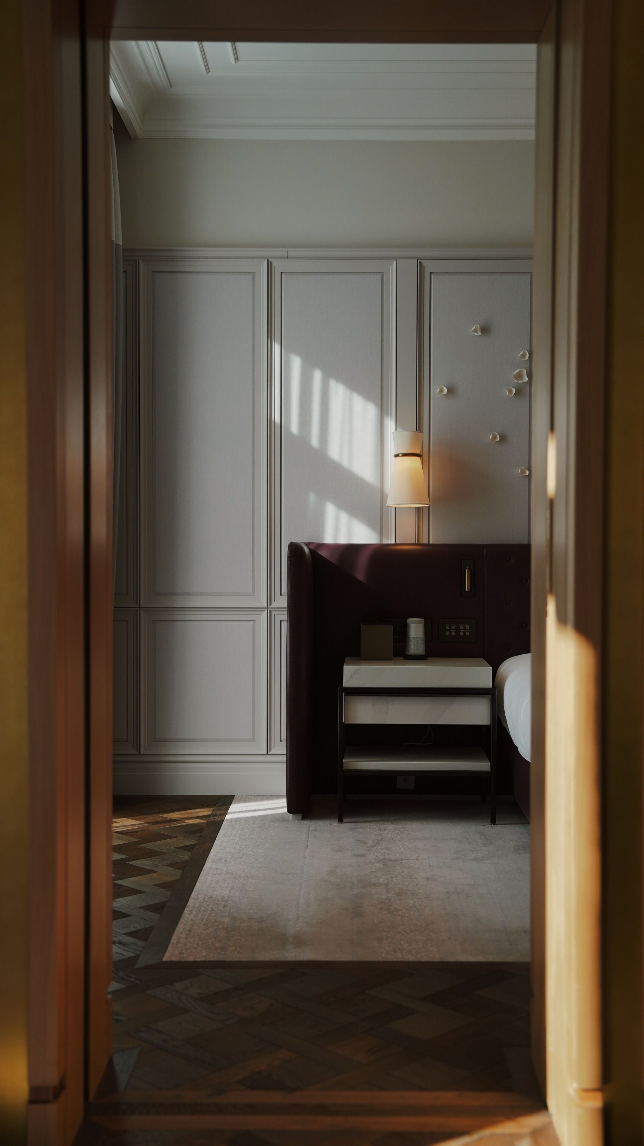 A hotel room with a bed, bedside table, lamp, and a view of the hallway.
