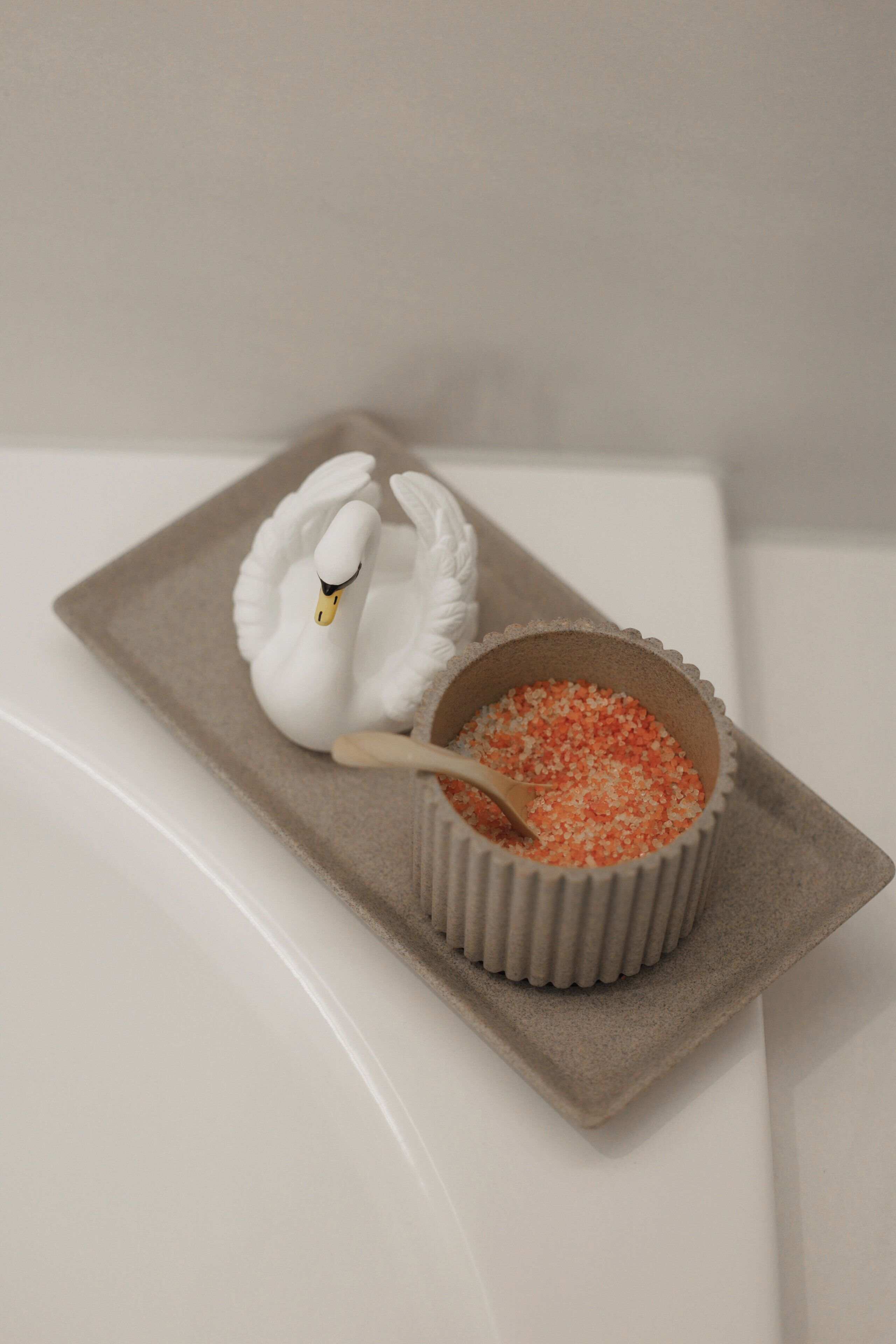 A swan-shaped dessert on a beige tray with a bowl of red and white sugar.