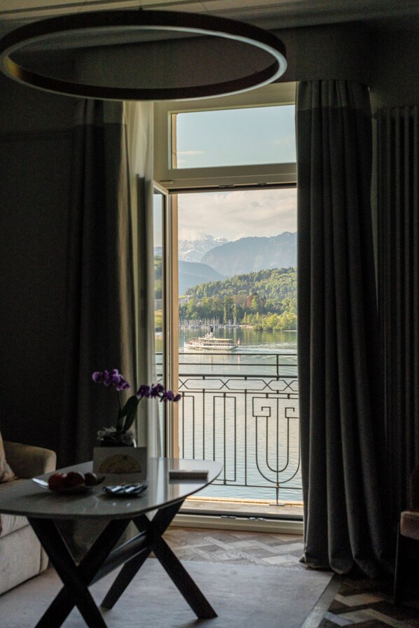 Une pièce avec vue sur un lac et des montagnes, une table ornée d’un vase de fleurs et un canapé.