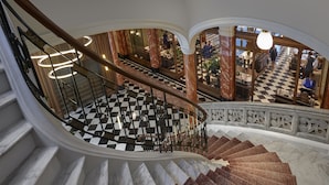 A grand staircase with a checkered floor, marble steps, and ornate railings.