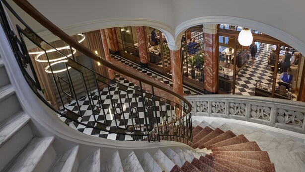 Un magnifique escalier avec un sol à carreaux, des marches en marbre et des rampes de garde-corps richement décorées.