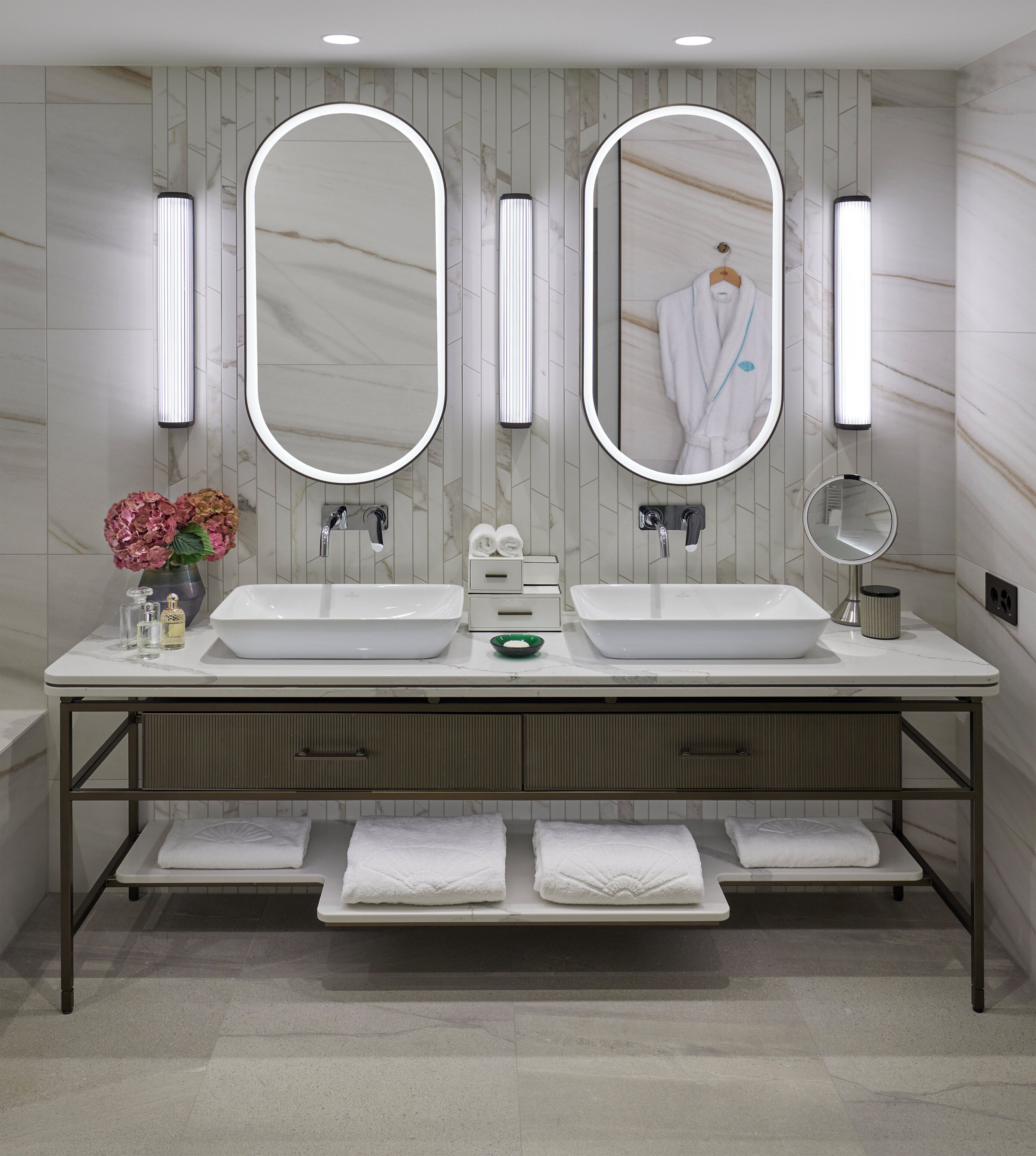 Un baño moderno con dos lavamanos, un espejo grande y un perchero para toallas.