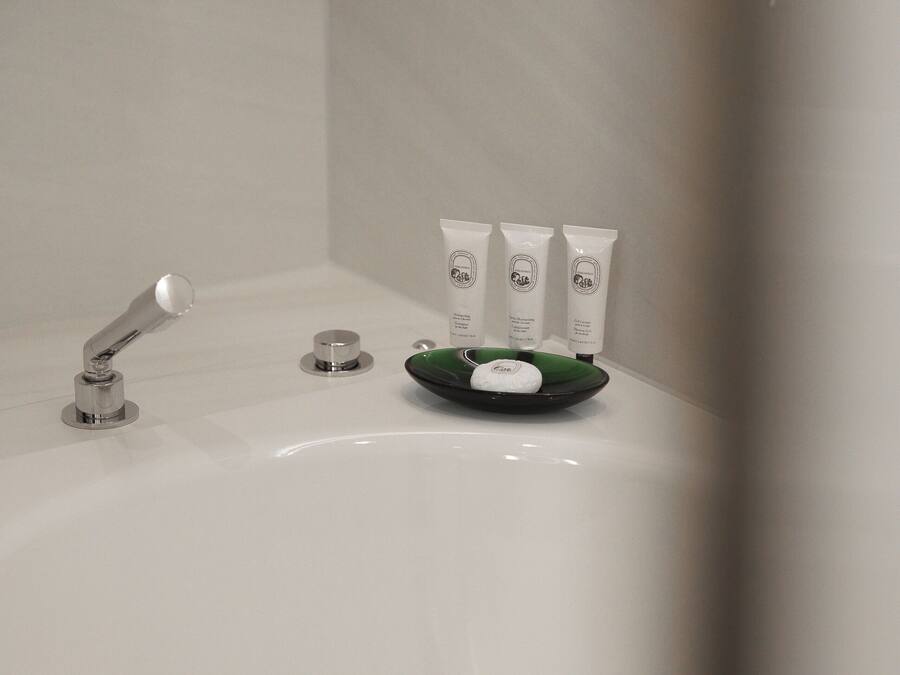 A bathroom with a white sink, a green soap dish, and three white toiletry containers.