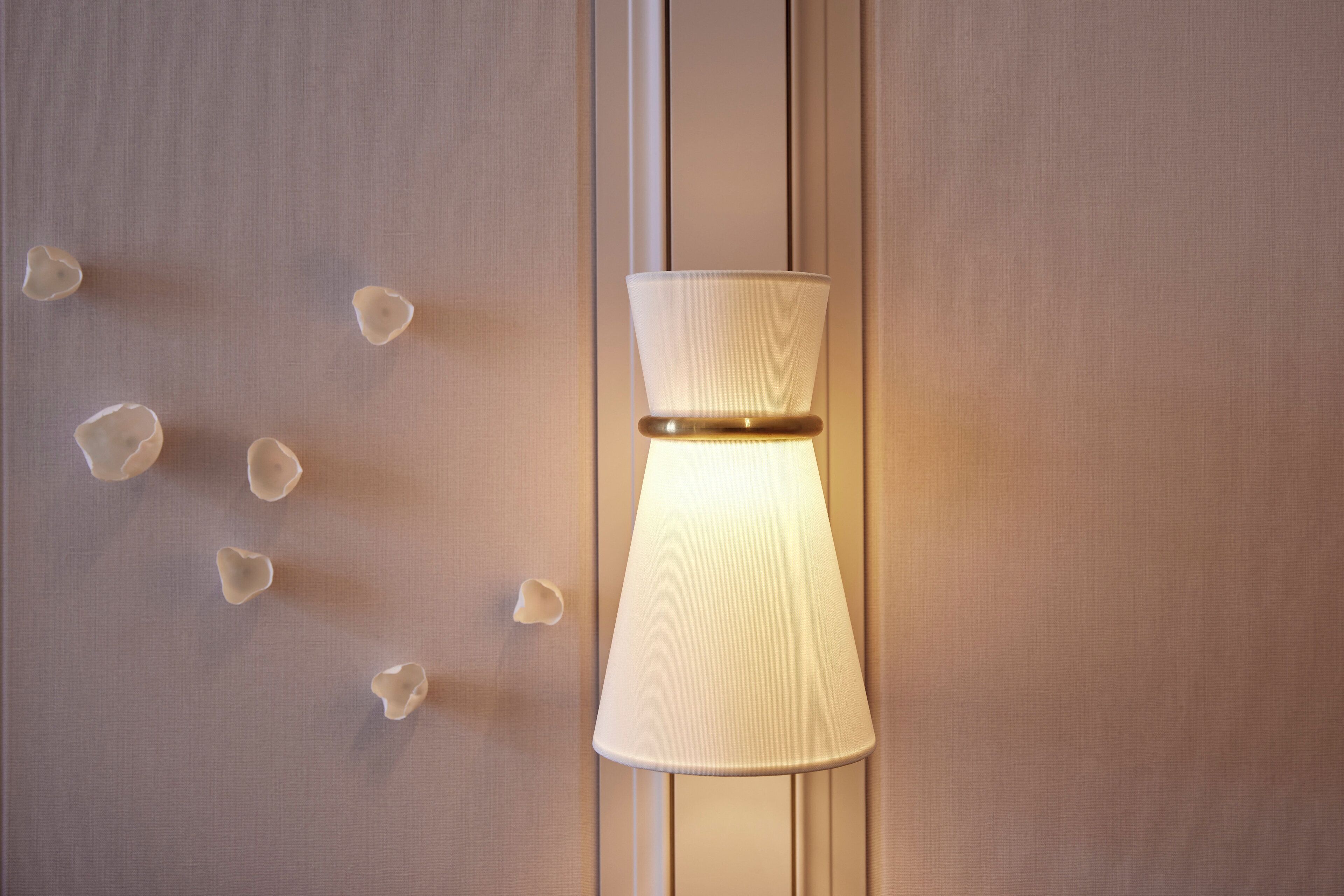 A wall-mounted lamp with a white shade and a gold accent.