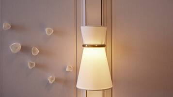 A wall-mounted lamp with a white shade and a gold accent.