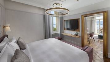 Habitación de hotel con una cama grande, un televisor montado en la pared, una ventana con cortinas y vistas al exterior.