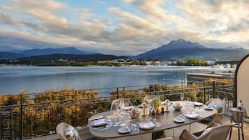 A dining table set for four with a view of a lake and mountains in the background.