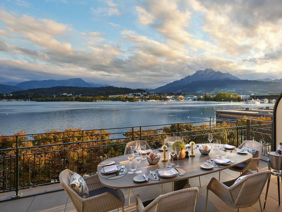 A dining table set for four with a view of a lake and mountains in the background.