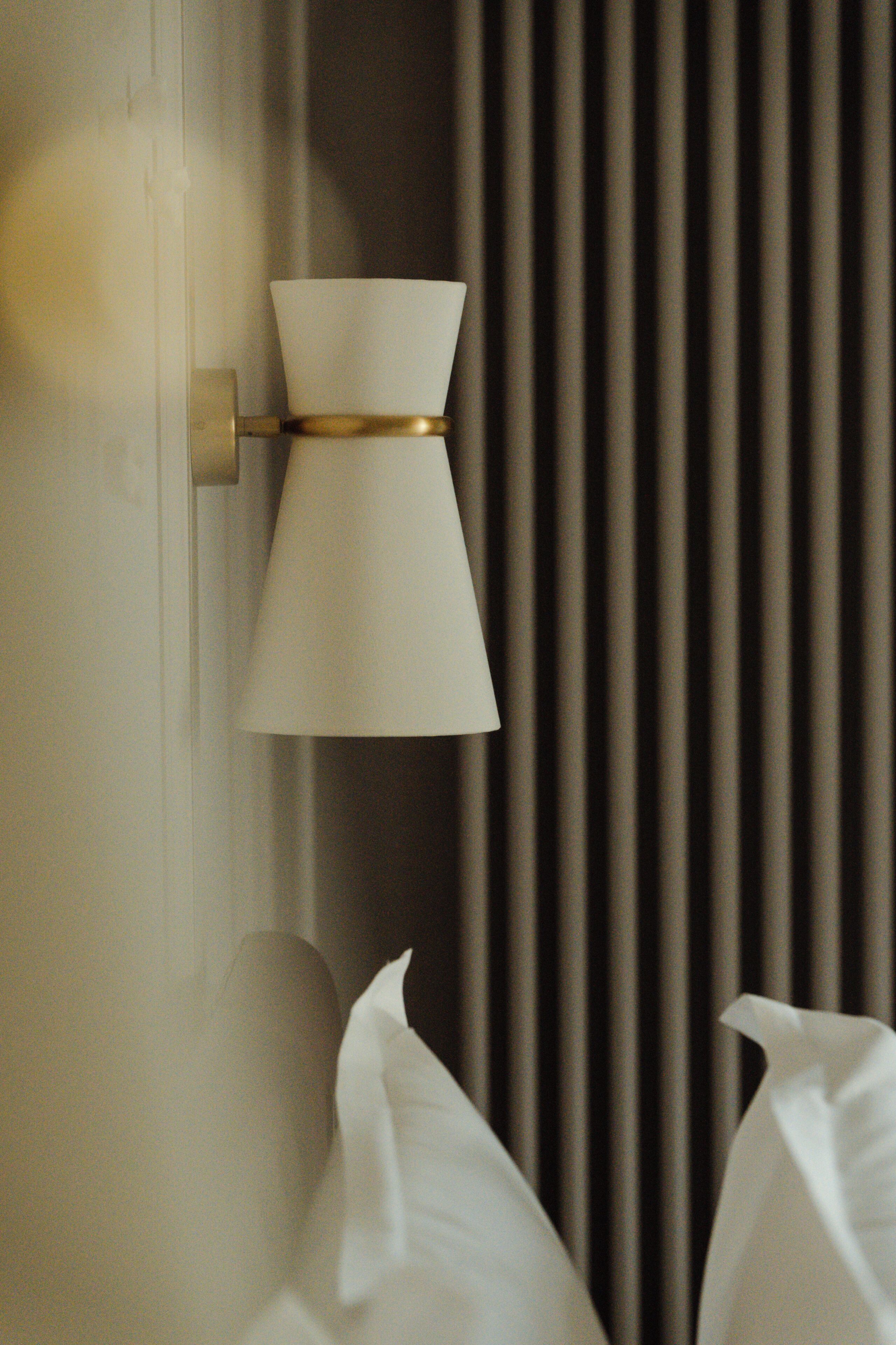 A wall-mounted lamp with a conical shade and a gold accent.