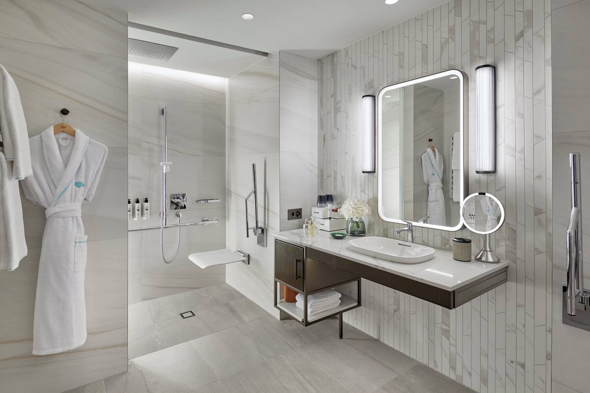 A modern bathroom with a walk-in shower, a vanity with a mirror, and a robe hanging on a rack.