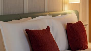 A hotel room with a bed, pillows, a wall-mounted lamp, and two framed artworks.