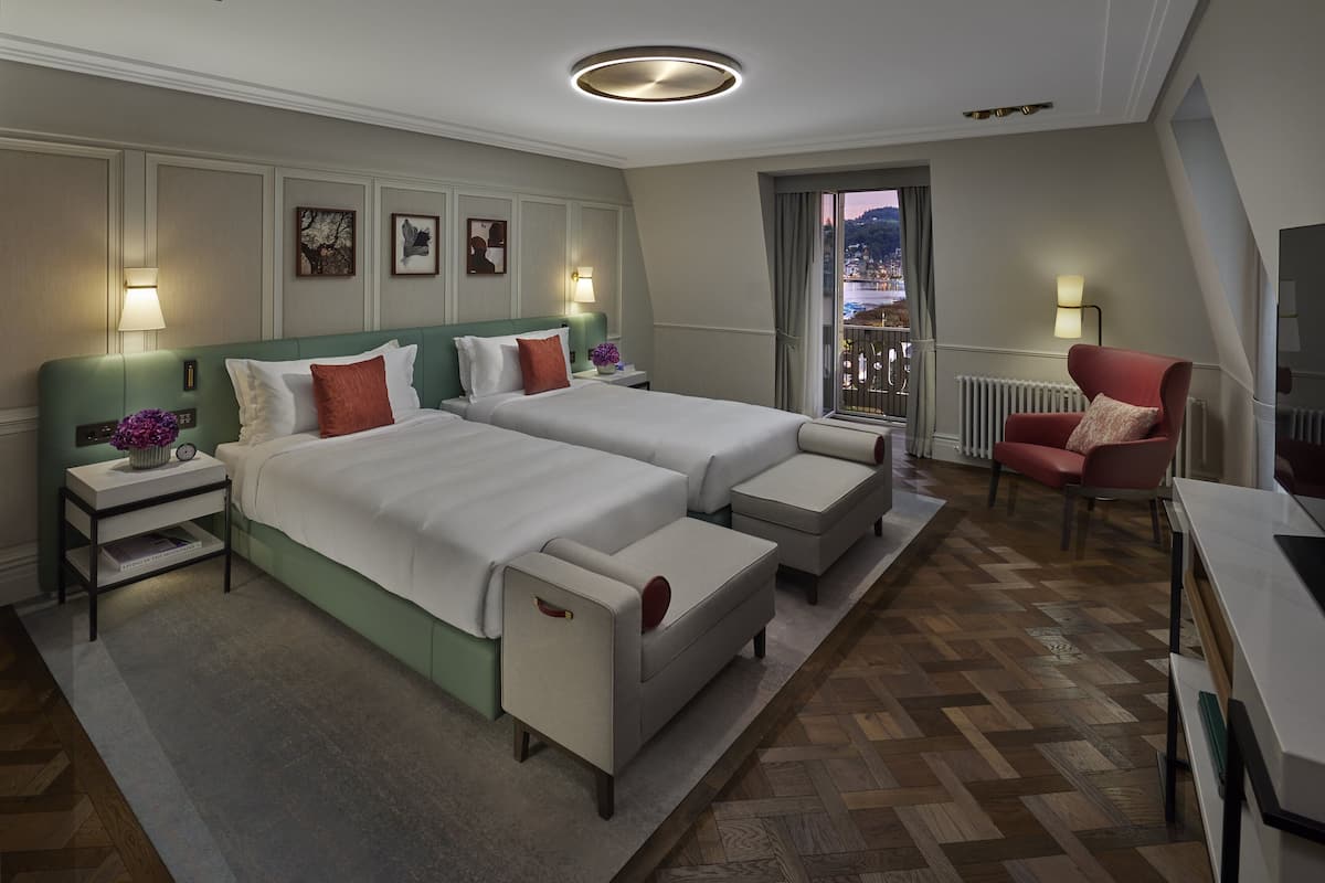 Hotellihuone, jossa on kaksi sänkyä, työpöytä, tuoli ja näkymä kaupunkimaisemaan.
