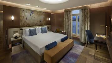 A modern hotel room with a large bed, a desk, and a view of the outdoors.