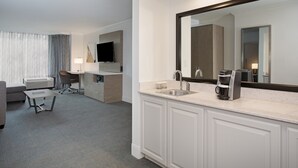 A hotel room with a large mirror, a sink, a coffee maker, a desk, and a television. - Crowne Plaza Costa Mesa Orange County by IHG (Costa Mesa)