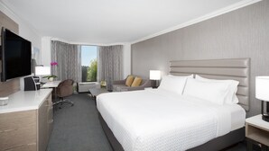 A hotel room with a large bed, a desk with a computer, a TV, and a window with curtains. - Crowne Plaza Costa Mesa Orange County by IHG (Costa Mesa)