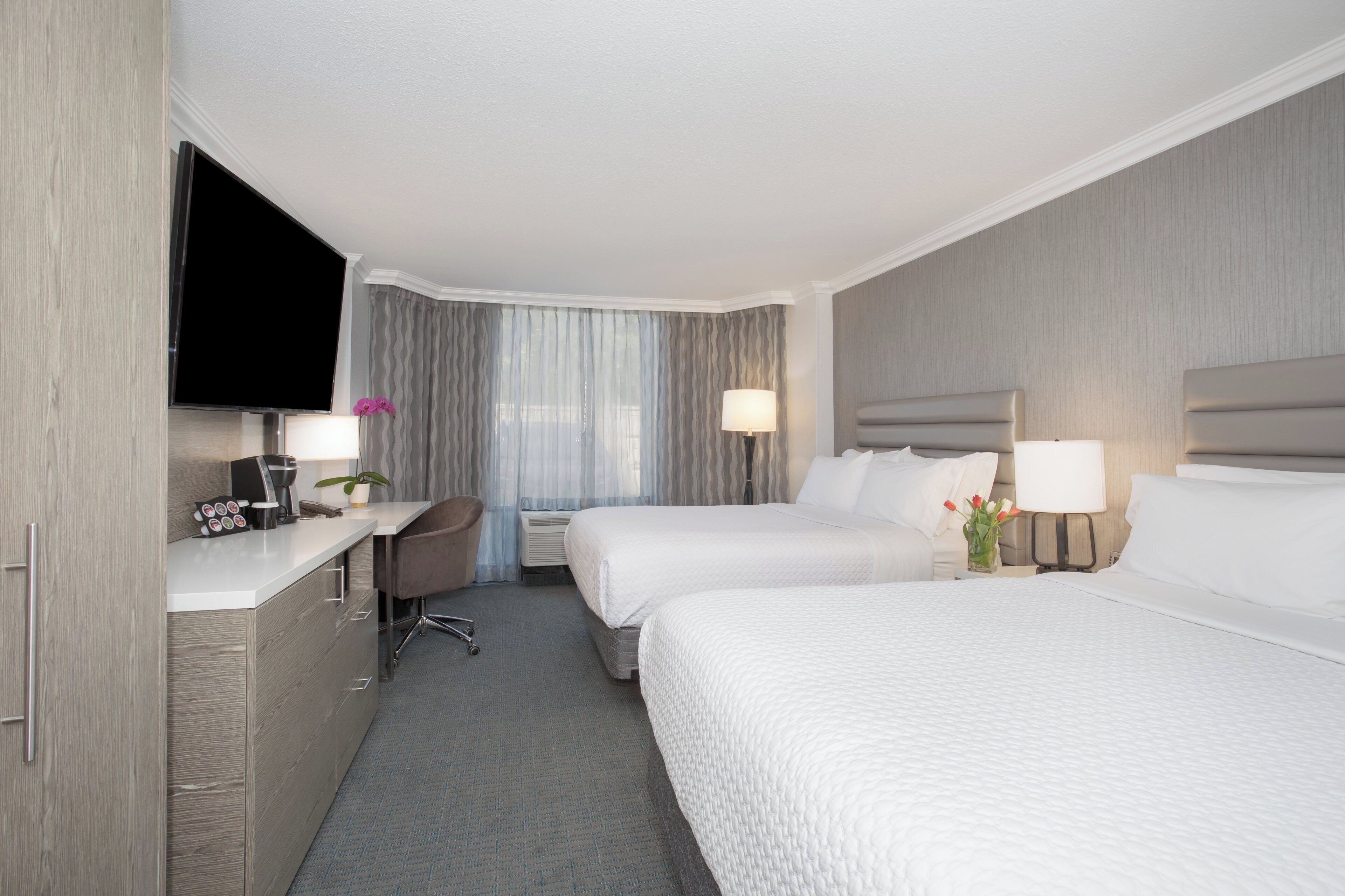 Habitación de hotel con dos camas, un escritorio, un televisor de pantalla plana y un minibar.