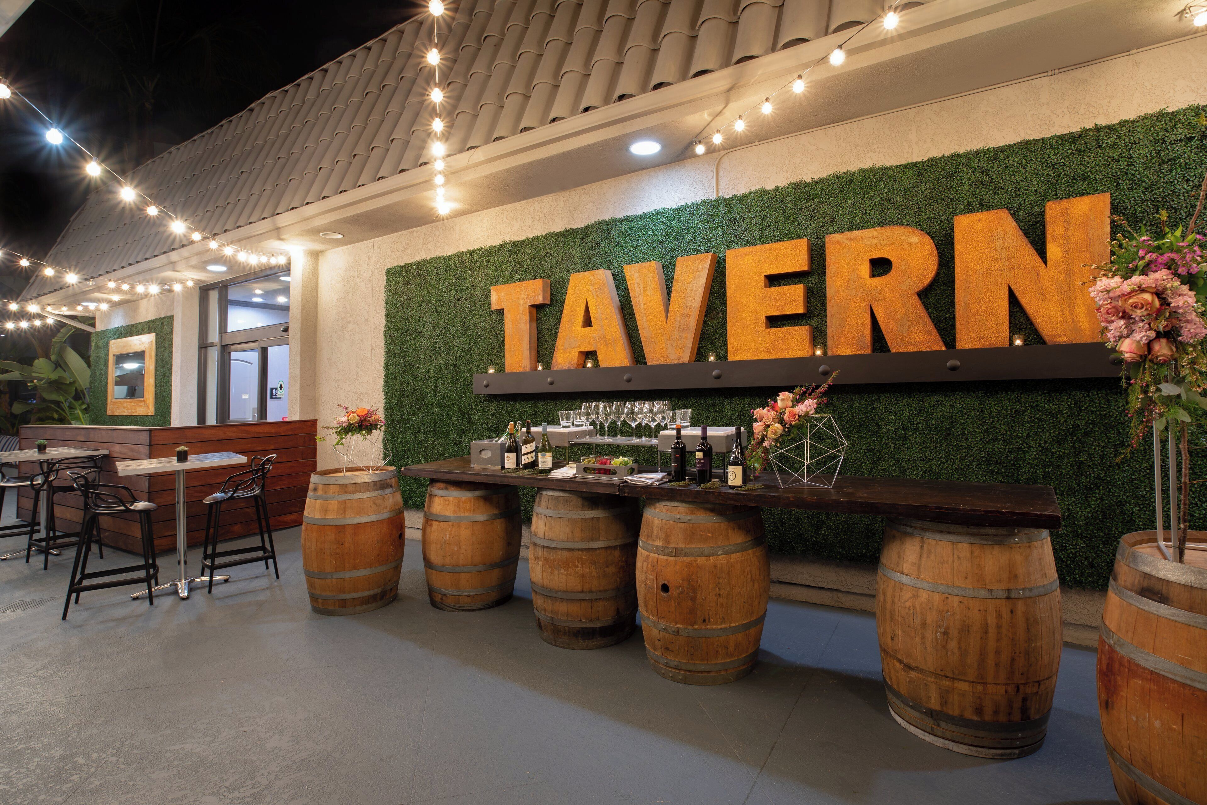 A bar area with a sign reading 'TAVERN' and wooden barrels.