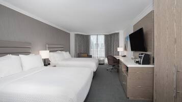 Habitación de hotel con dos camas, un escritorio, una silla, un televisor y una cafetera.
