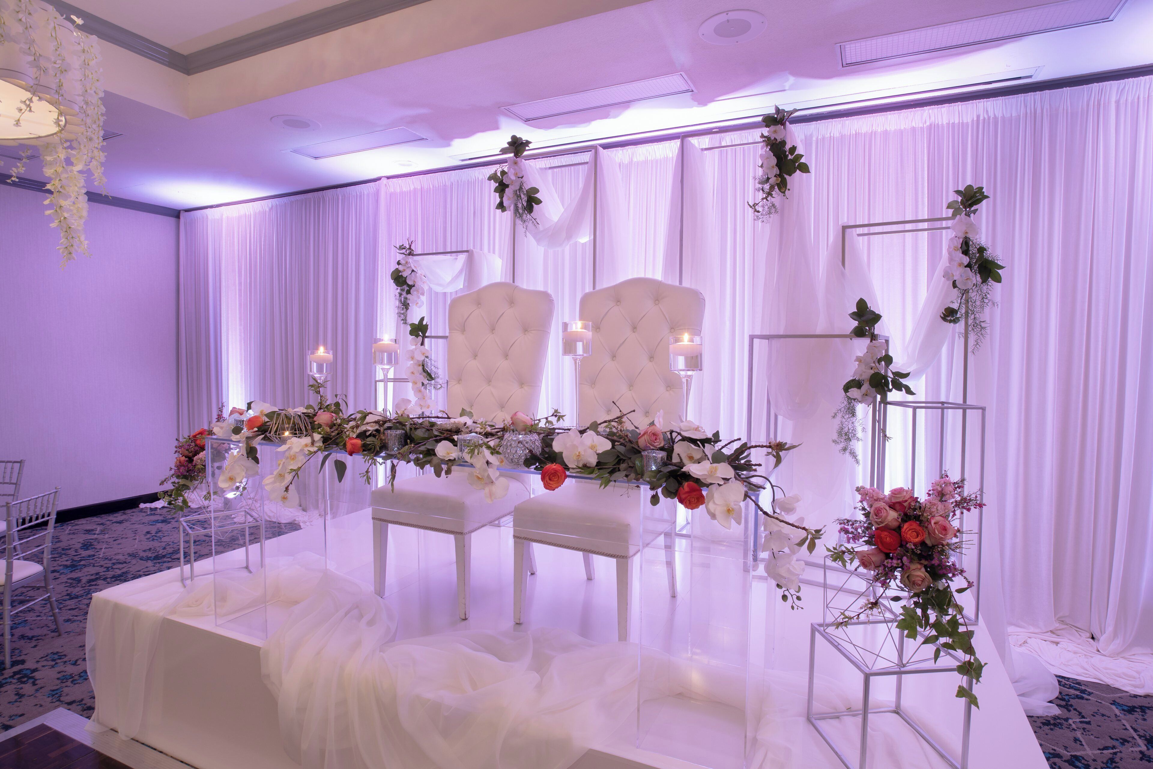 A wedding reception setup with a white table, chairs, and floral decorations.