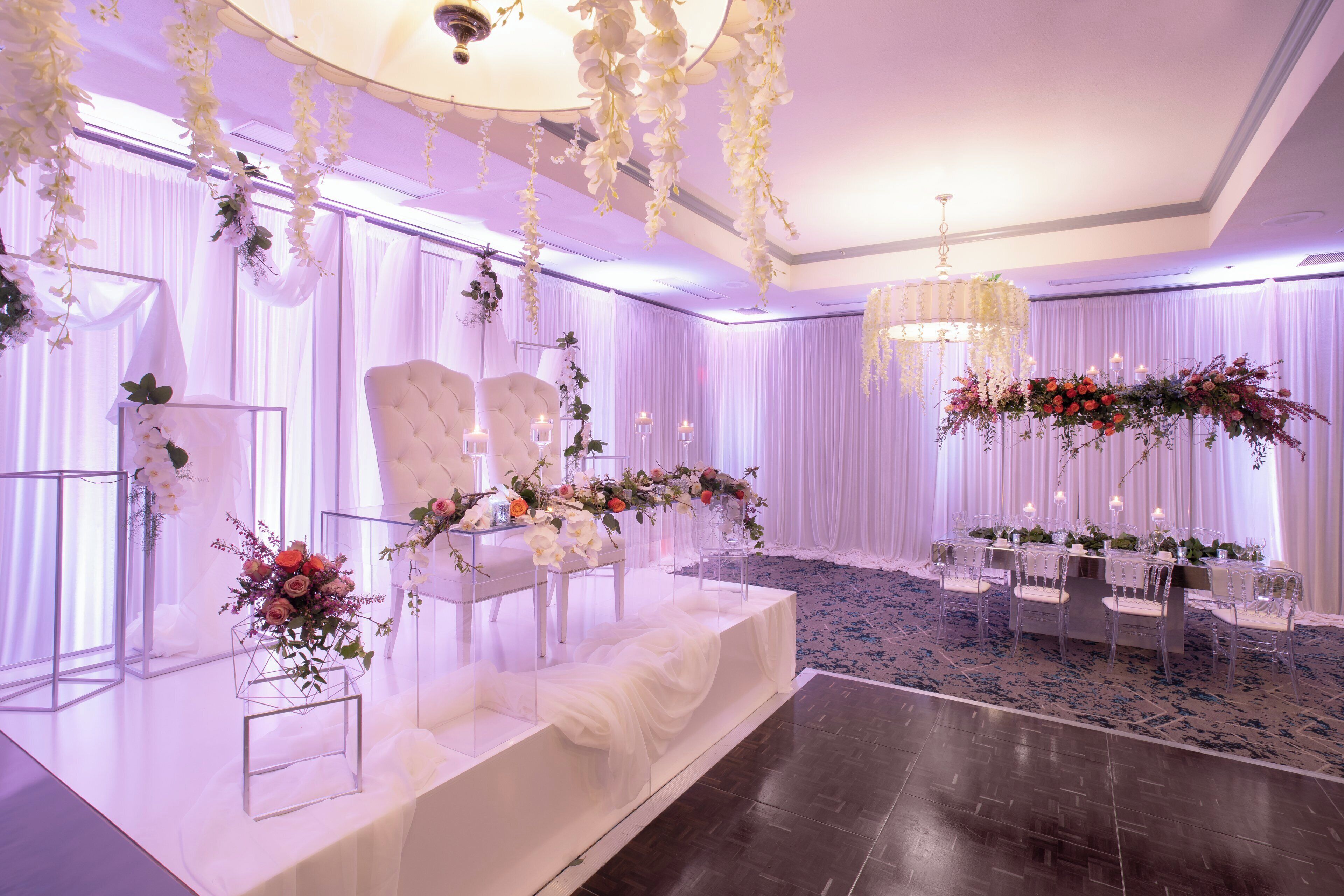 A wedding reception area with a stage, seating, and floral decorations.