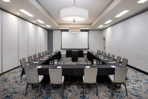 A conference room with a long table, chairs, a projector screen, and a chandelier. - Crowne Plaza Costa Mesa Orange County by IHG (Costa Mesa)