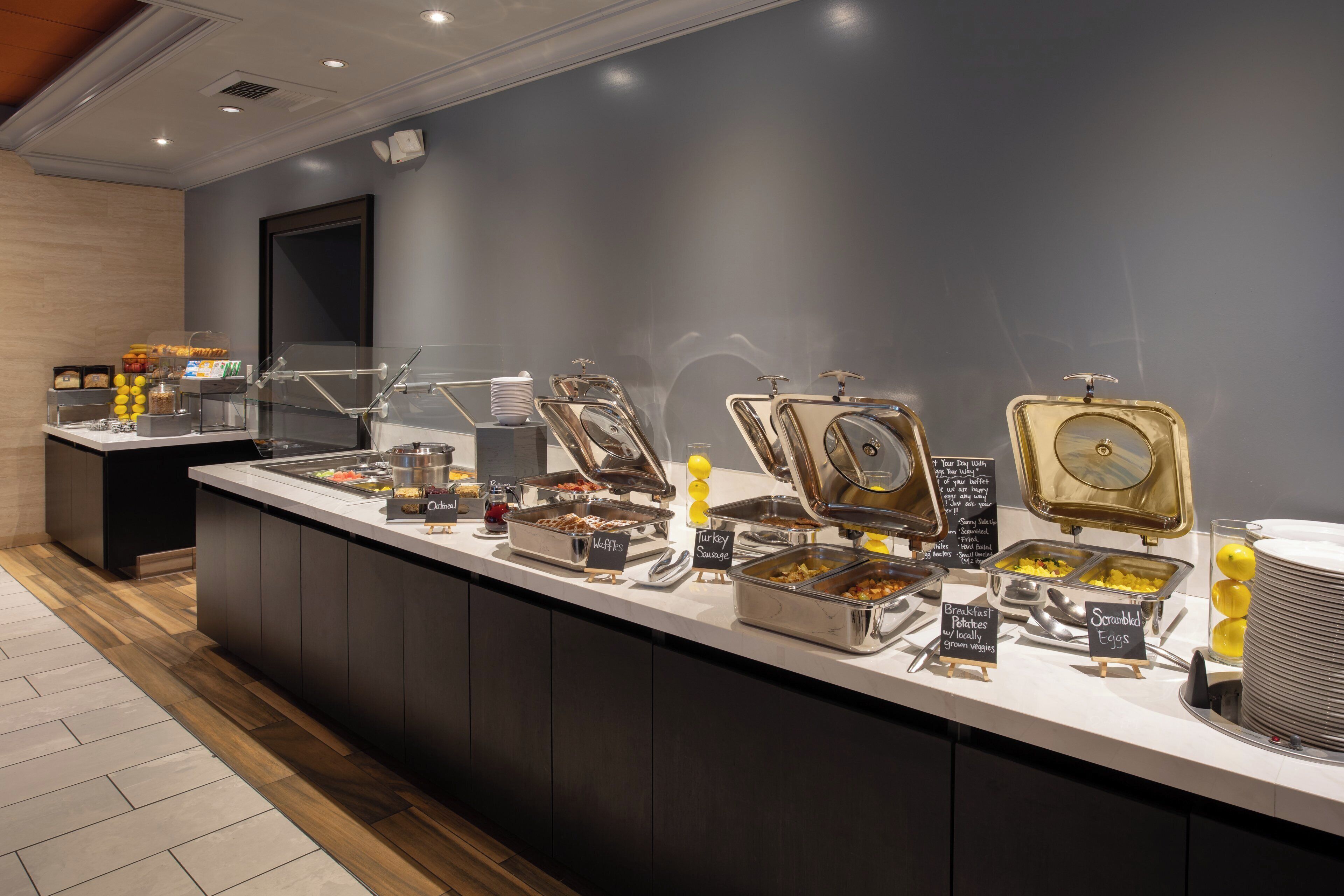 A buffet setup with various food items and a sign indicating breakfast options.