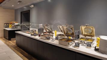 A buffet setup with various food items and a sign indicating breakfast options.
