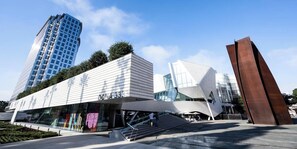 Un edificio moderno con fachada de vidrio, una escalera destacada y una escultura metálica única.