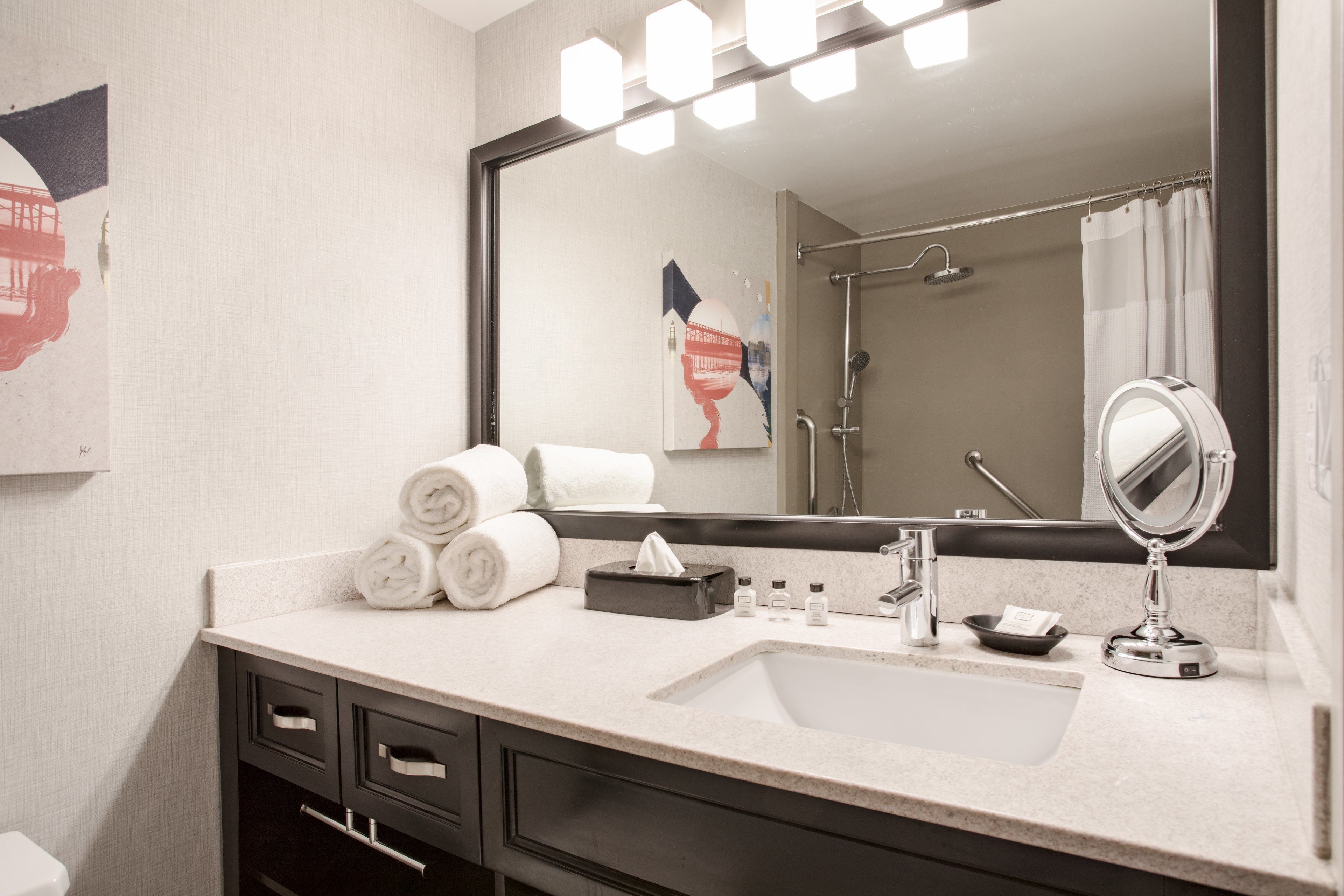 A bathroom with a sink, mirror, and towel dispenser.