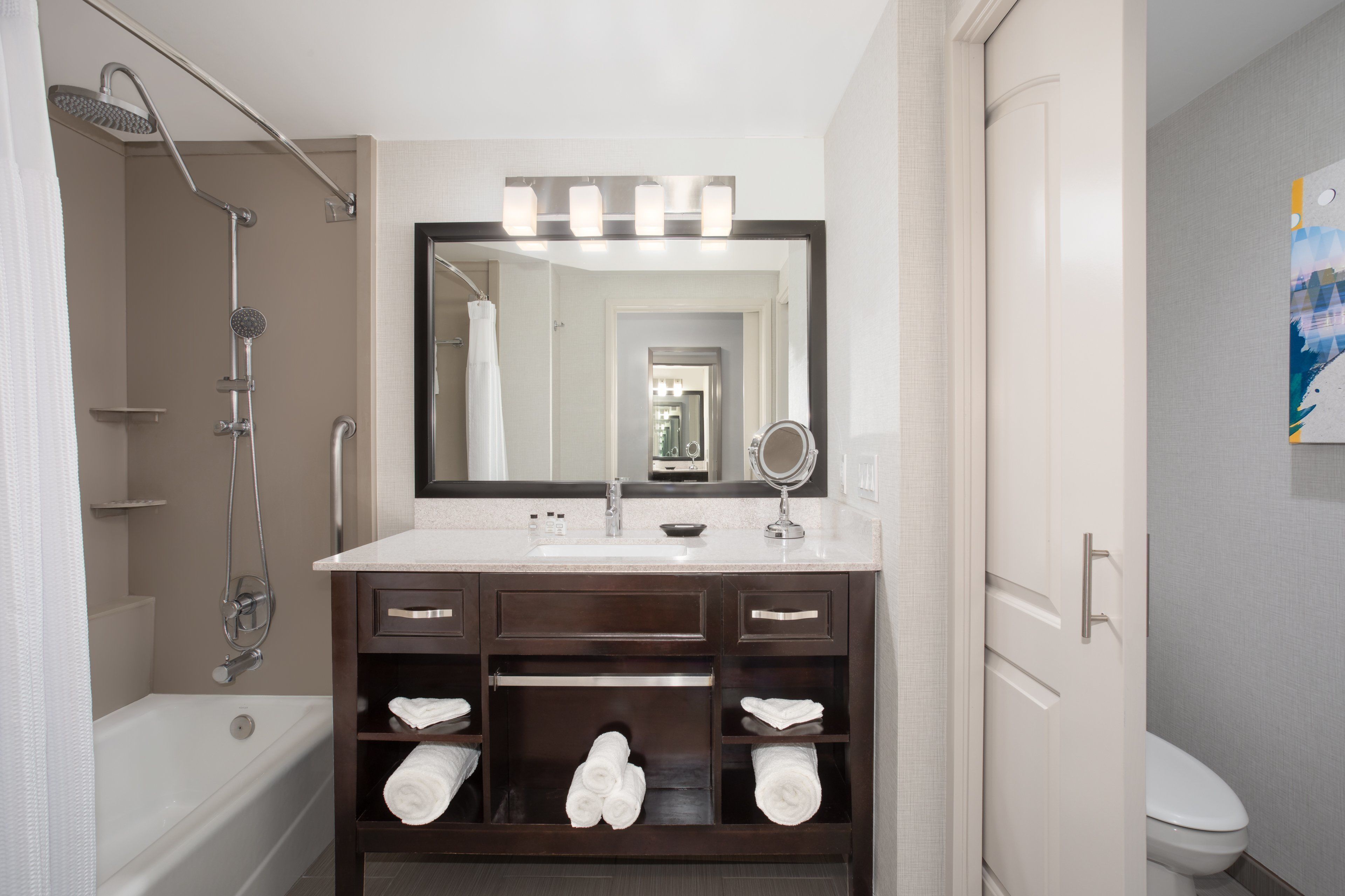 A modern bathroom with a bathtub, a vanity with a mirror, and a toilet.