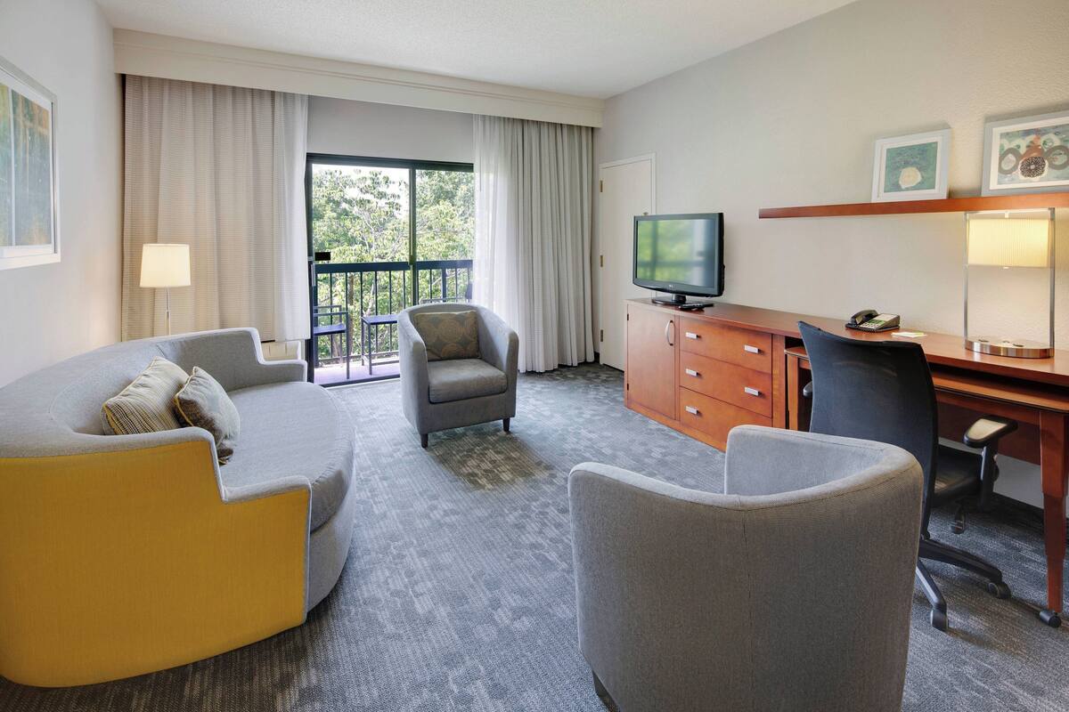 Une chambre d’hôtel équipée d’un canapé, d’un fauteuil et d’un espace bureau.