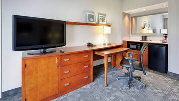 Une chambre d’hôtel équipée d’un bureau en bois, d’une télévision, d’un four à micro-ondes, d’une machine à café et d’une chaise.