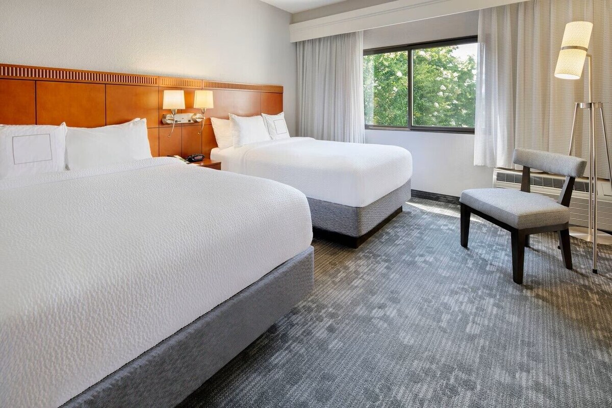 Ett hotellrum med två sängar, ett skrivbord och en stol.