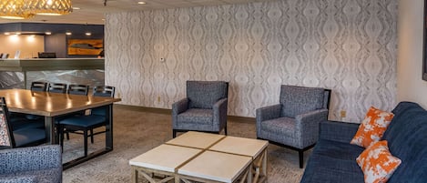 A modern hotel lobby with a dining area, seating arrangements, and a reception desk.