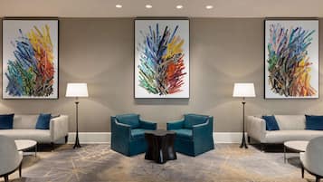 A modern hotel lobby with two sofas, a coffee table, and two floor lamps.