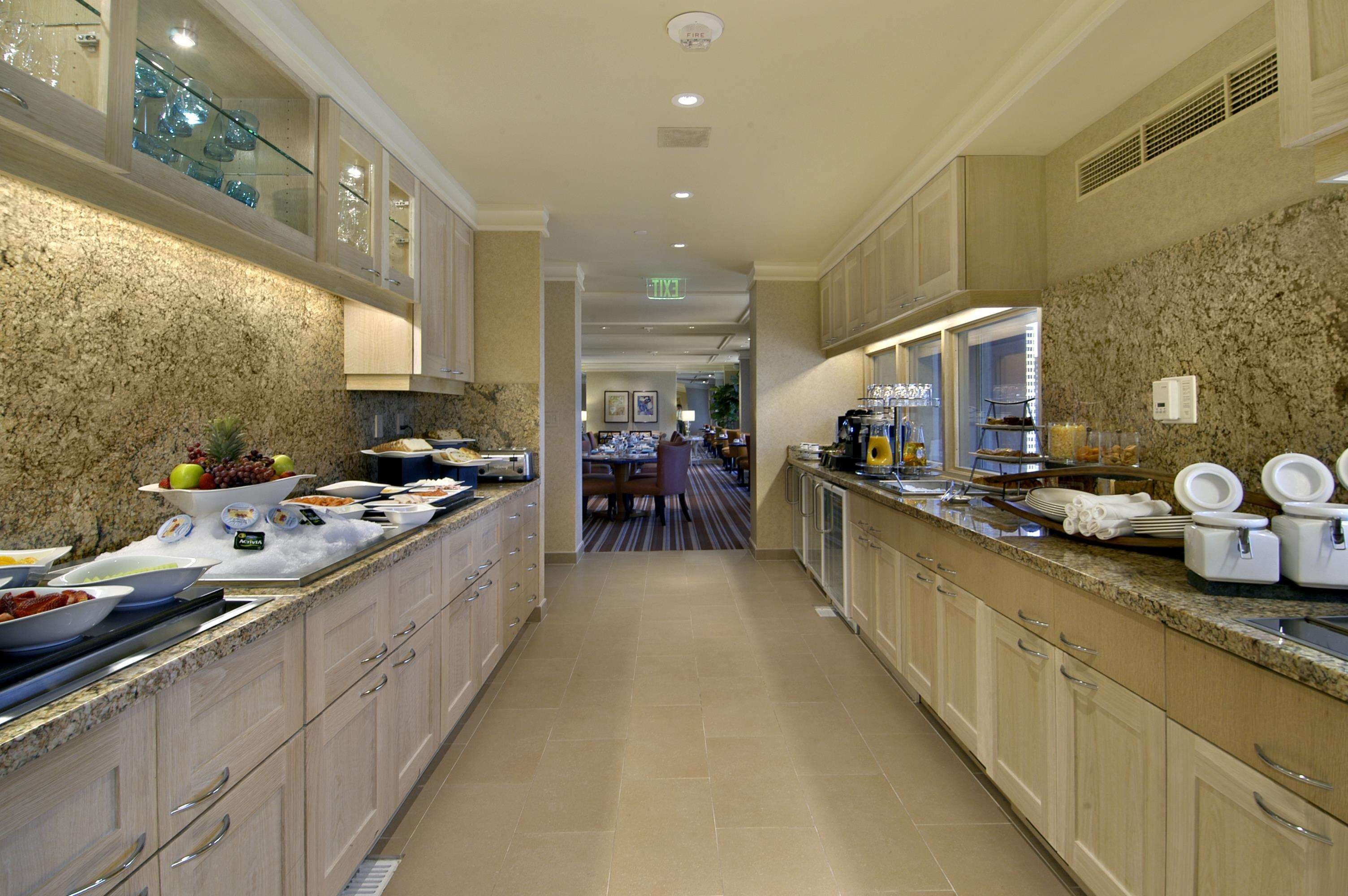 A hotel kitchen with granite countertops, stainless steel appliances, and a buffet setup.