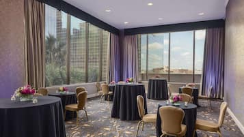 A conference room with round tables, chairs, and floral centerpieces.