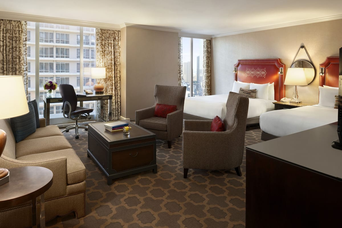A hotel room with a large bed, a desk with a chair, a sofa, and a coffee table.