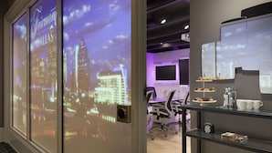 Un salón de conferencias con una proyección de la ciudad, una estación de café y un reloj en la pared.