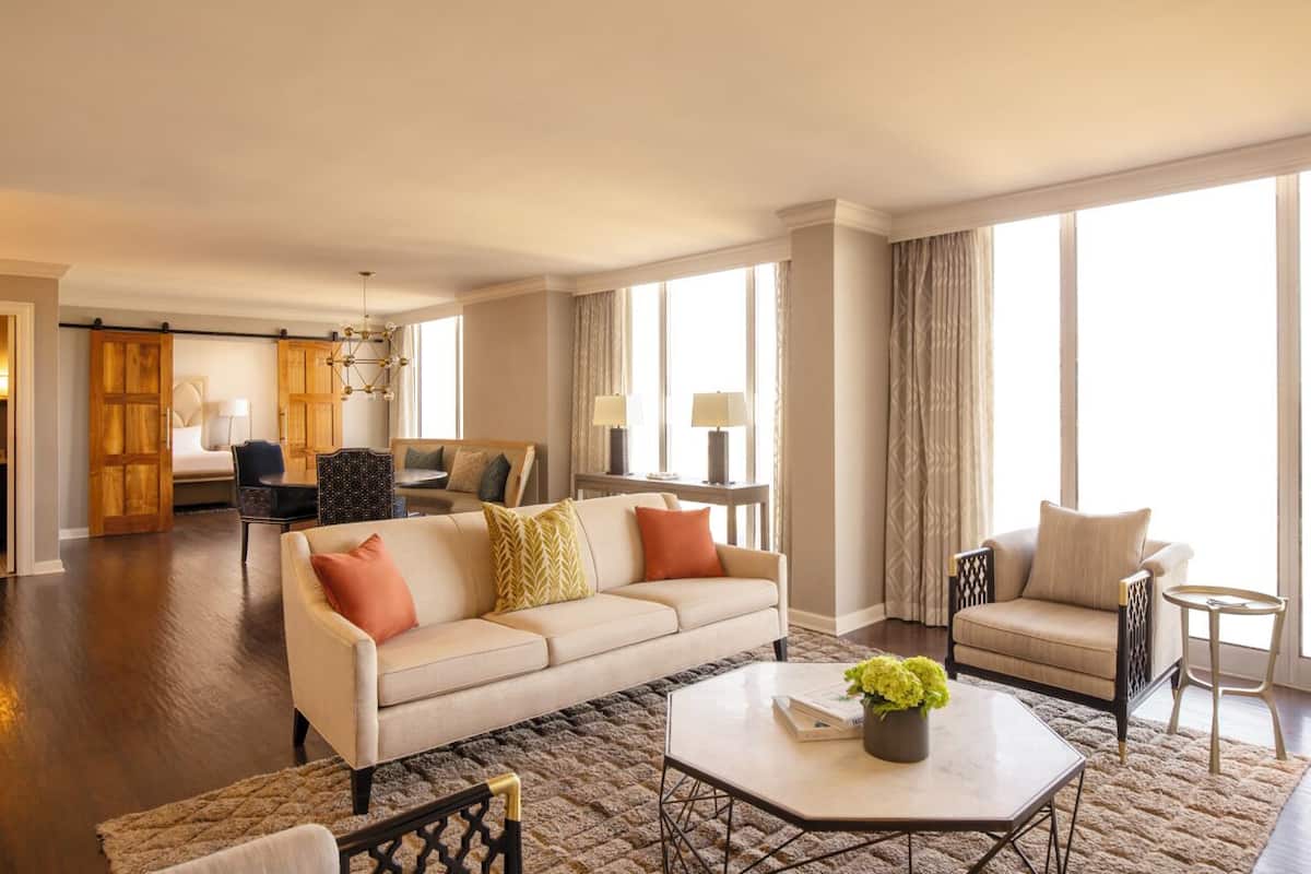 A spacious living room with a large sofa, a coffee table, and a dining area with a chandelier.