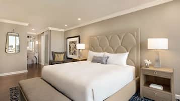 A large bed with a tufted headboard, bedside tables with lamps, a bench, and a framed picture on the wall.