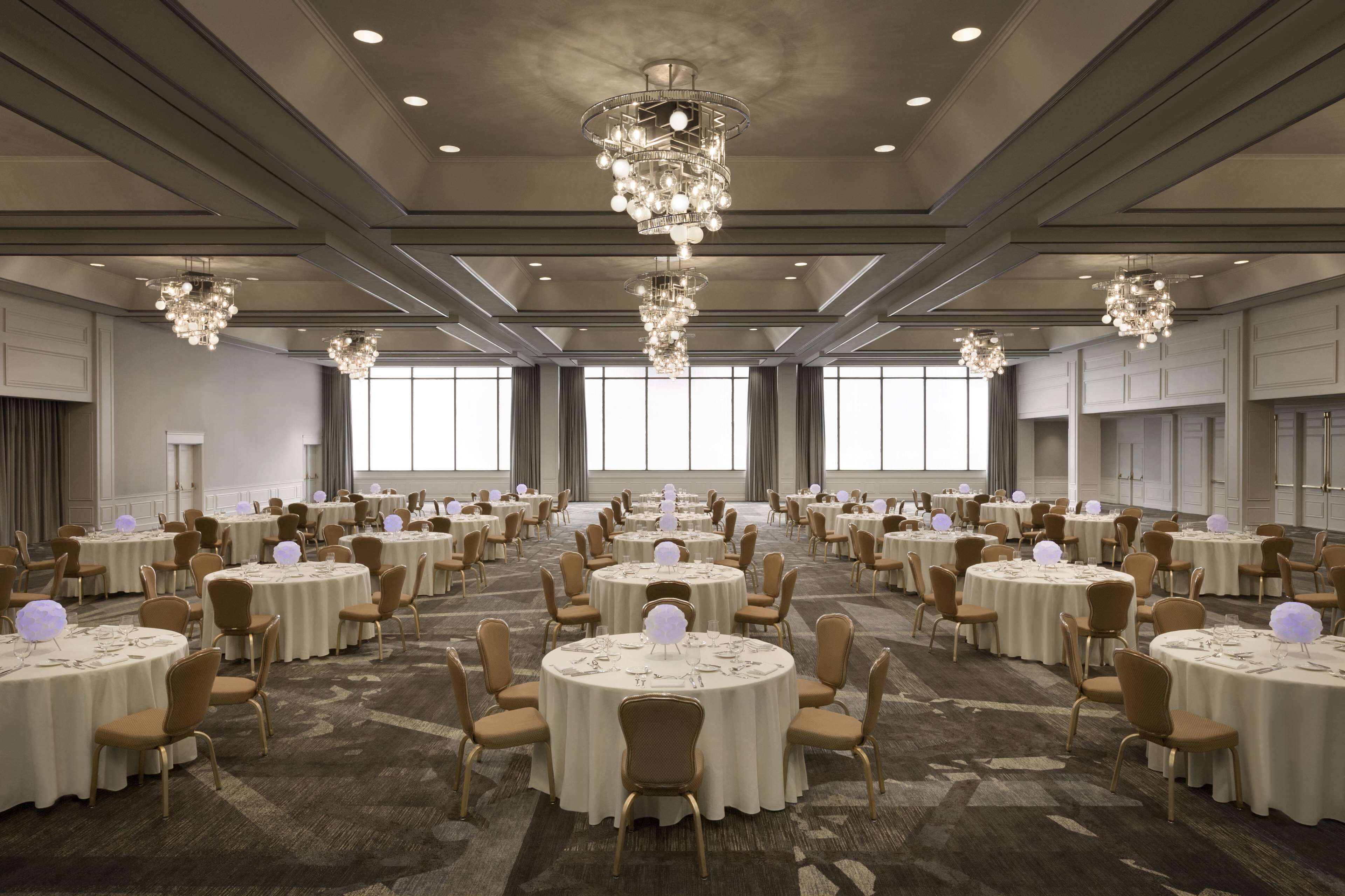 Un amplio salón de banquetes con mesas redondas, sillas y candelabros.