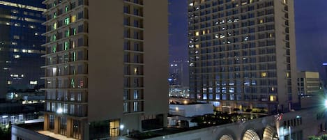 A high-rise hotel with multiple floors, a prominent clock on the facade, and a well-lit street in the foreground.