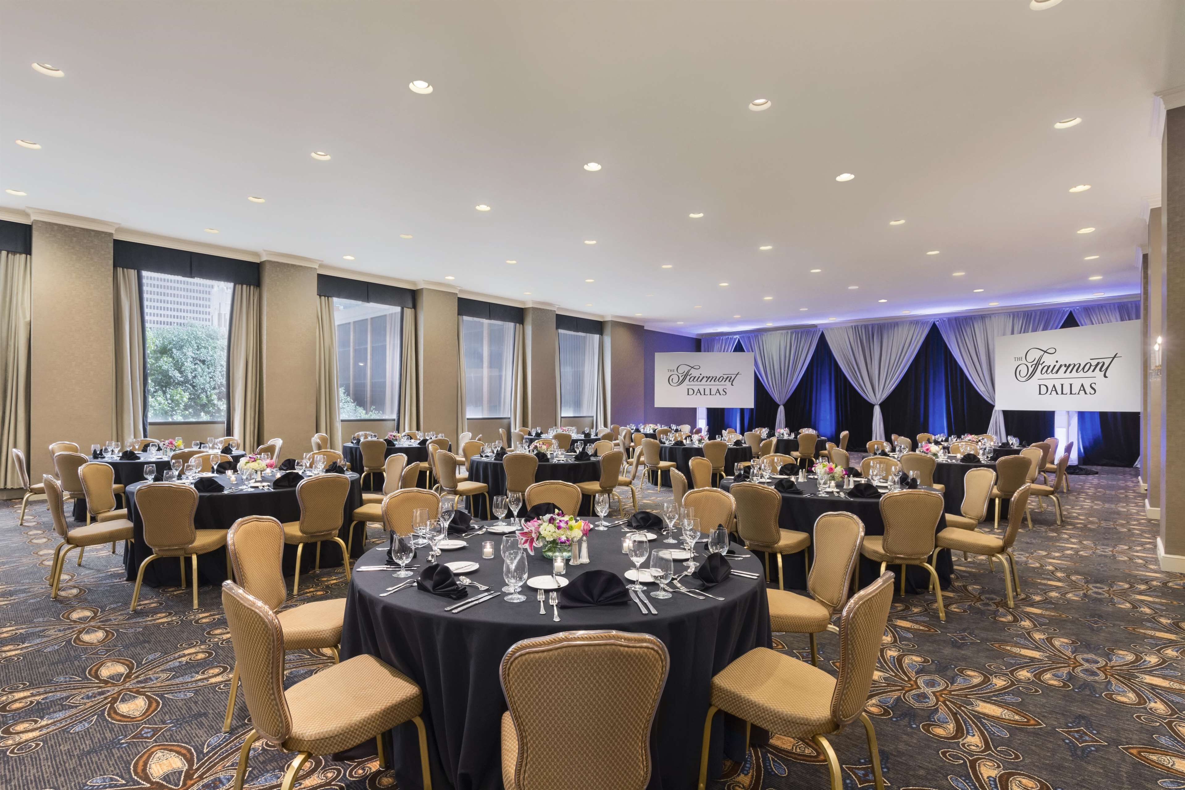 A banquet hall with round tables, chairs, and a carpeted floor.