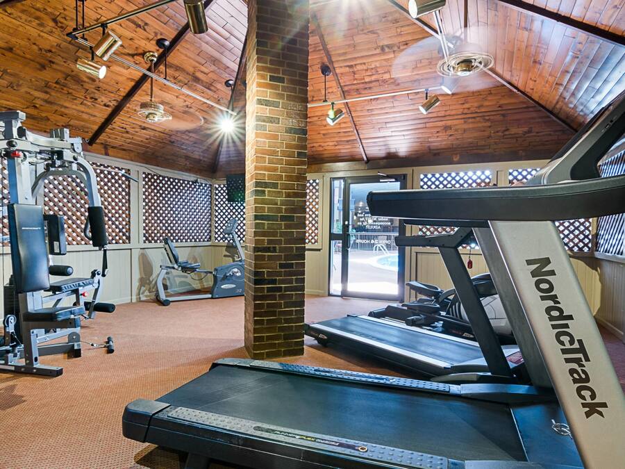 Een sportschool met loopbanden, krachtapparaten en een bakstenen pilaar.