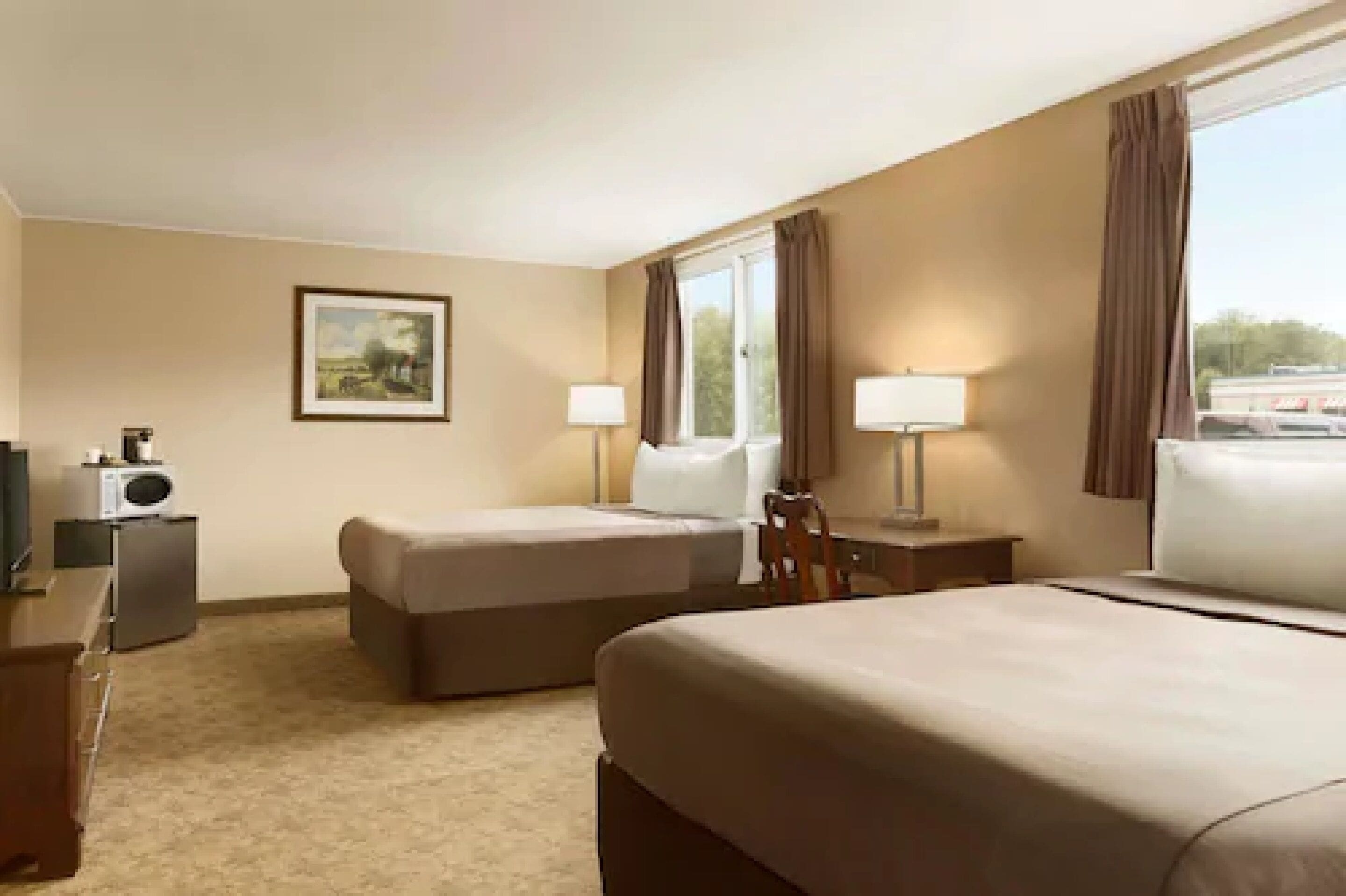 Habitación de hotel con dos camas, un escritorio, una silla, un televisor y una ventana con cortinas.