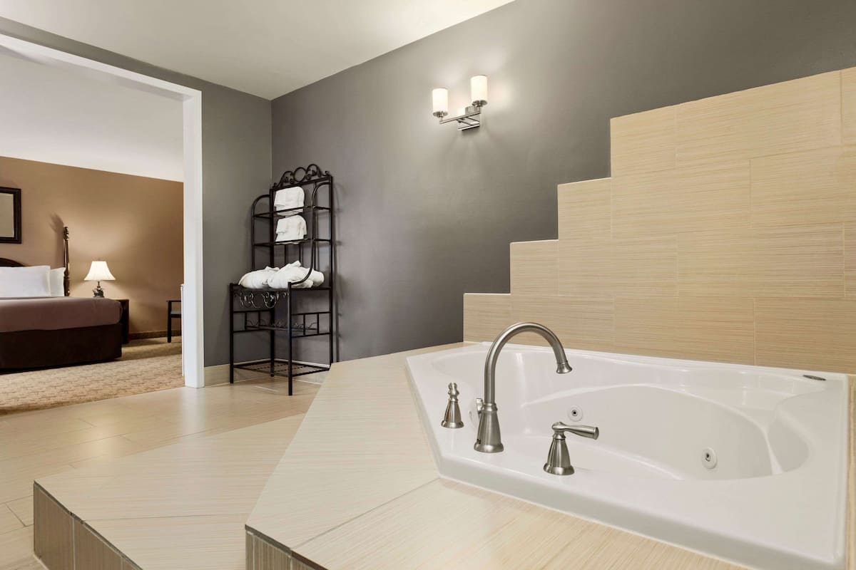 A modern bathroom with a large bathtub, a towel rack, and a staircase.