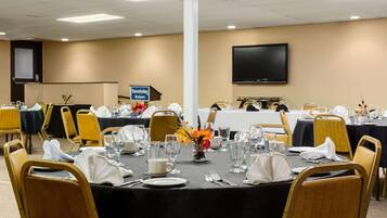 Une salle de conférence avec des tables disposées pour une réunion, équipée de porte-noms, de verres à eau et d’une enseigne indiquant « Travelodge ».